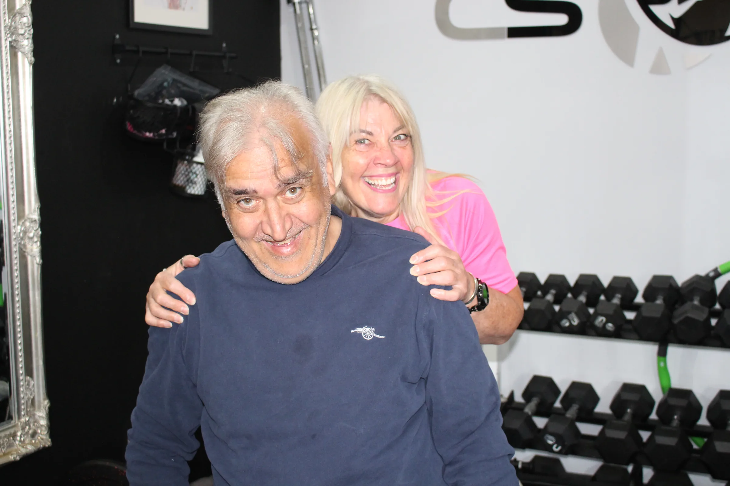 Carol laughing with a client in the studio, an arm around his shoulders.