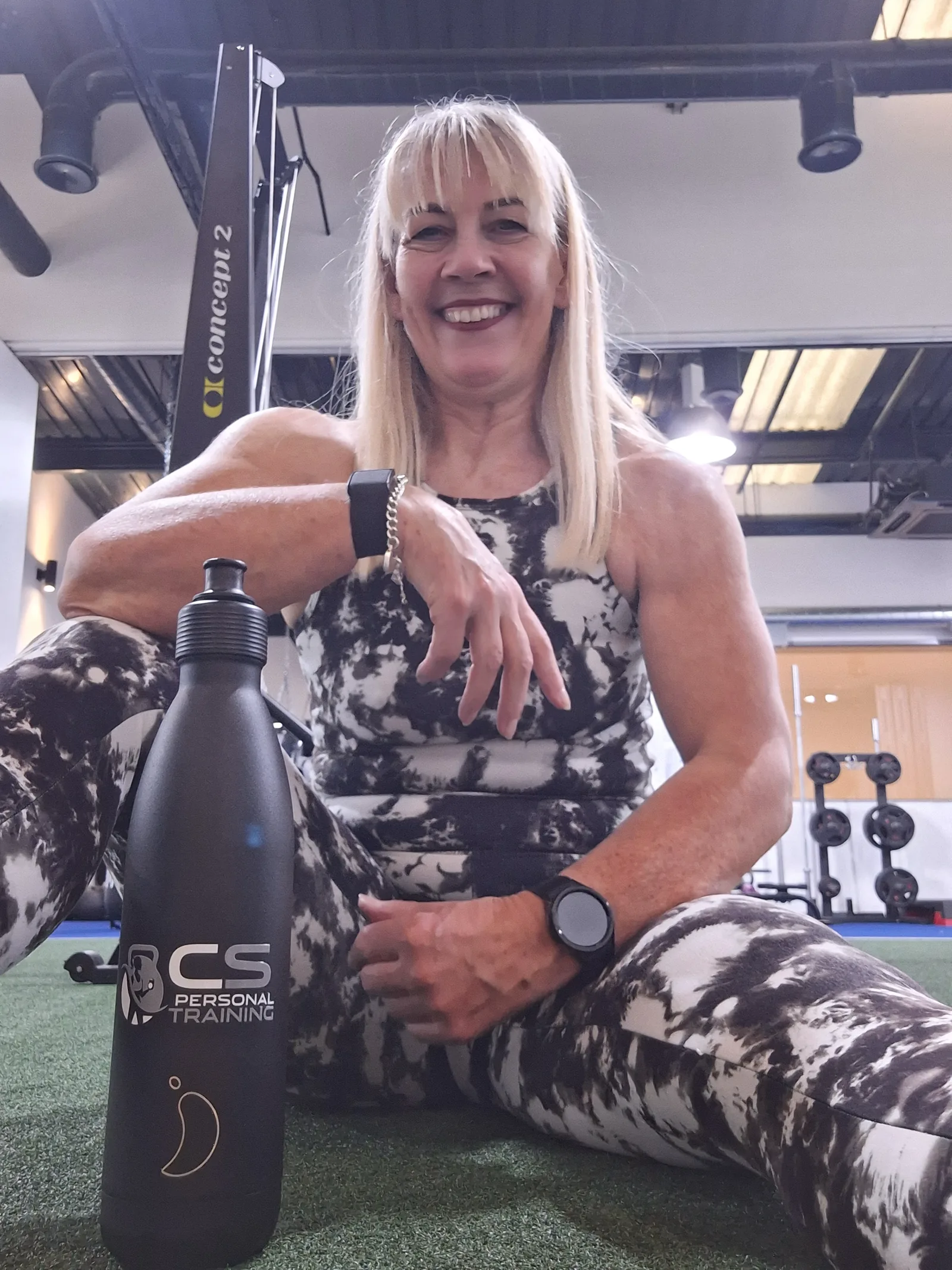 Carol sitting beside a CS Personal Training water bottle, laughing.